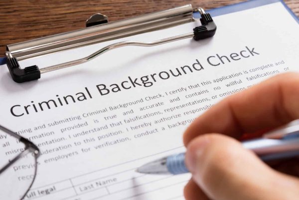 Close-up Of Person Hand Filling Criminal Background Check Application Form