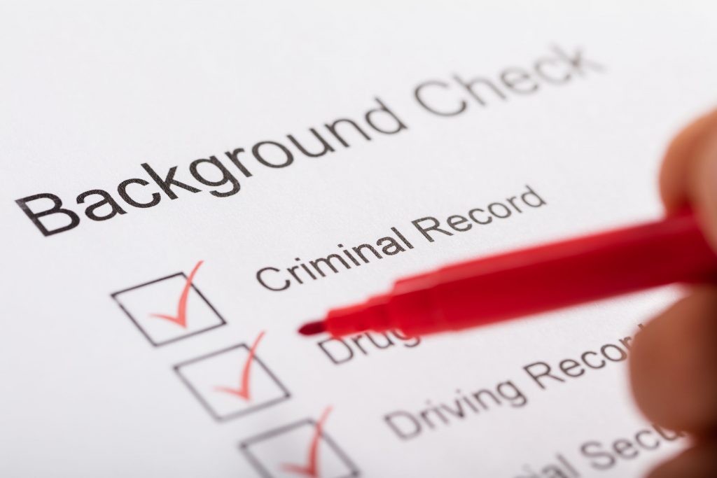 Close-up Of Person Hand Ticking Off Checkboxes In Background Check Form