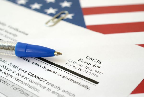 I-9 Employment Eligibility Verification blank form lies on United States flag with blue pen from Department of Homeland Security close up