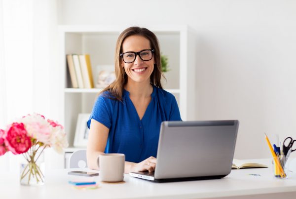 business, people and technology concept - happy smiling woman with laptop computer working at home or office