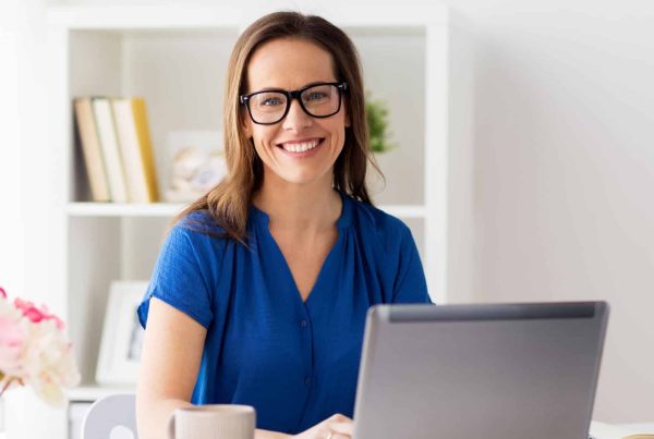 business, people and technology concept - happy smiling woman with laptop computer working at home or office